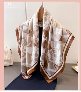 Detail of elegant floral silk scarf in coffee and beige hanging on a wooden hanger
