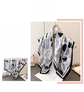 Close-up of elegant black and white floral silk scarf with geometric stripe edges