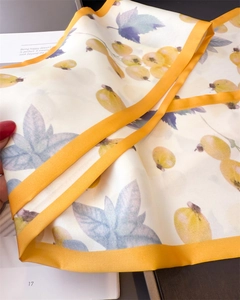 Detailed macro view of yellow berry print silk scarf with bright yellow border trim