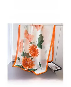 Detailed macro view of ivory silk scarf with large orange floral print and vibrant wide borders