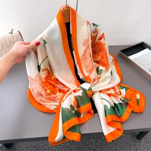 Elegant ivory silk satin scarf featuring orange floral prints and a contrasting border
