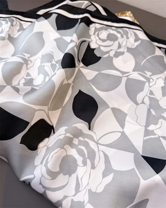 Detailed view of silk satin scarf featuring monochrome camellia flower print and striped borders