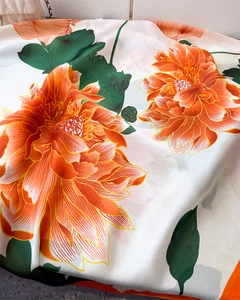 Macro detail of silk scarf showing vibrant orange floral patterns and smooth texture