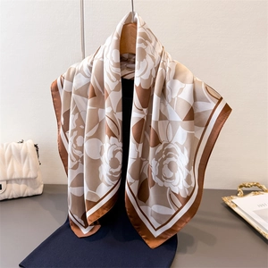 Elegant rose print faux silk square scarf with brown borders styled on a gold tray