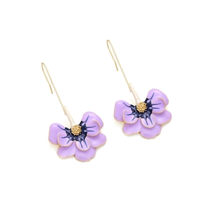 Gros plan détaillé de boucles d'oreilles fleurs en émail violet avec pistils dorés