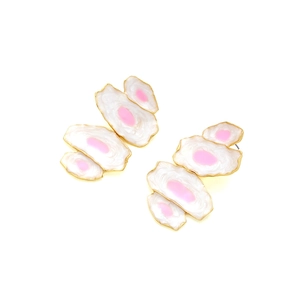 Détail de boucles d'oreilles fleurs en émail blanc avec centre rose et bords dorés