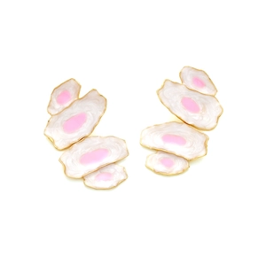 Détail macro de boucles d'oreilles abstraites avec émail rose et bordure dorée