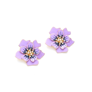 Détail macro de boucles d'oreilles fleurs en émail violet avec bords dorés et cristaux