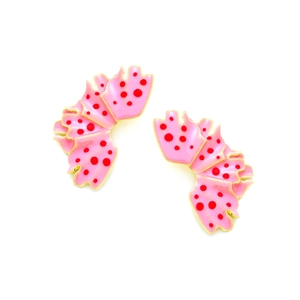 Macro shot of pink enamel leaf earrings with red polka dots and gold metallic edges
