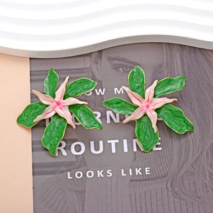 Boucles d'oreilles fleurs en émail avec feuilles vertes et pétales blanc rose sur magazine