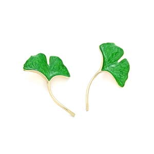 Macro detail of green enamel ginkgo leaf earrings with golden metal leaf edges