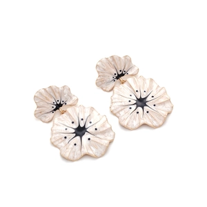 Detail of cream enamel flower earrings with black center and golden alloy frame