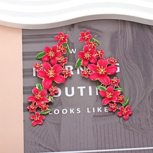 Gros plan détaillé des boucles d'oreilles fleur en émail rose vibrant avec bordure dorée