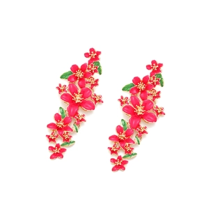 Détail de boucles d'oreilles fleurs en émail rose avec étamines dorées et feuilles