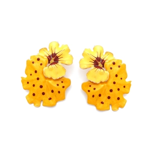 Detail view of yellow enamel flower earrings with red dots and brown center