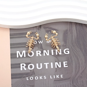 Detailed view of gold metal scorpion earrings on a fashion magazine background