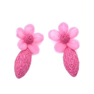 Détail de boucles d'oreilles en raphia rose avec fleurs délicates en tulle