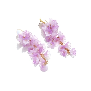 Dettaglio dei lunghi orecchini a mughetto viola con nappe di fiori in vetro opaco