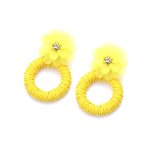 Close-up of bright yellow resin flower earrings with woven rattan hoops and crystals