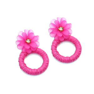 Detail of fuchsia resin flower earrings with raffia woven hoops and rhinestone center