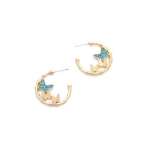 Detail of C-shaped gold bamboo hoops with dark blue crystal butterfly accents
