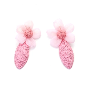 Détail de boucles d'oreilles fleurs en tulle rose avec pendentifs feuilles en raphia
