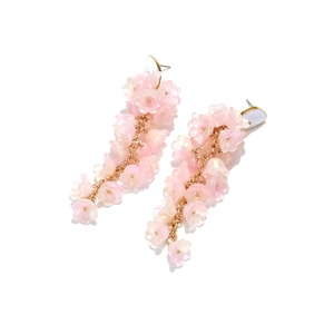 Dettaglio delle nappe di fiori in resina rosa e orecchini a catena dorata delicata