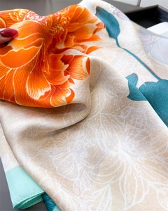 Detailed macro view of orange floral satin silk scarf with elegant jacquard fabric texture