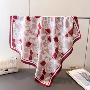 Elegant rose print silk square scarf in burgundy and pink hanging on a metal rack