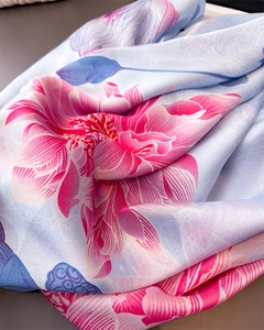 Detailed view of silk-like scarf featuring pink lotus pattern on light blue fabric