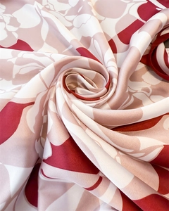 Macro detail of red rose print satin scarf showing smooth silk texture and drape