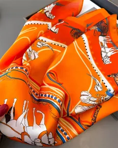Detail of orange satin scarf showing elegant horse and carriage print with silky texture
