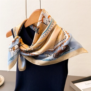 Elegant silk scarf with vintage carriage print tied on a dark vest on a wooden hanger