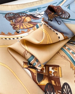 Detail of silk-feel scarf featuring vintage carriage print in gold and light blue