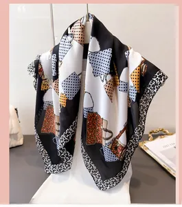 Detailed close-up of a leopard print silk scarf with luxury handbag patterns on a hanger