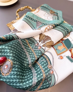 Close-up of silk square scarf with horse carriage and chain pattern on gold tray