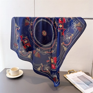 Detail of luxury navy blue silk scarf with vintage carriage and gold chain patterns