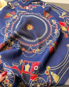 Detailed close-up of dark blue silk scarf with vintage golden carriage and chain patterns