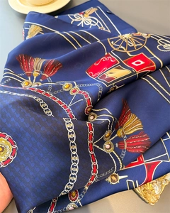 Detail of silk scarf with vintage gold chains and red tassels on deep blue satin
