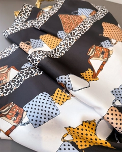 Detailed close-up of leopard print satin scarf featuring various handbag patterns and silk texture