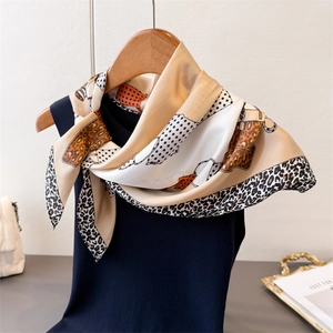 Detail of leopard print silk scarf styled on a navy top with chain and polka dot patterns