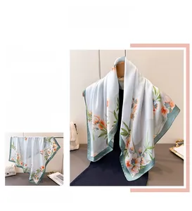 Gros plan détaillé du foulard en soie à imprimé floral avec bords verts et motifs bleus