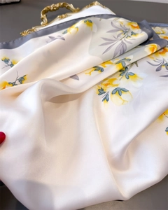 Gros plan du foulard en soie à fleurs sur un plateau doré vintage avec texture fine