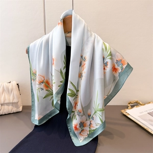 Foulard fleuri en soie synthétique vert clair suspendu sur un cintre en bois chic