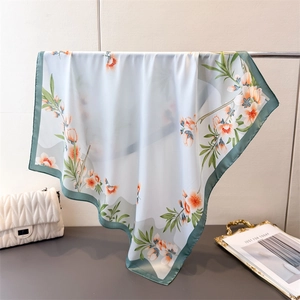 Détail d'un foulard en soie florale aux bords verts montrant la texture satinée lisse