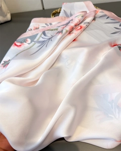 Détail macro d'un foulard en soie avec imprimés floraux roses et texture lisse fine