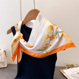 Gros plan d'un foulard en soie imprimé tulipes avec bordure orange sur haut en maille