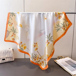 Détails de texture du foulard en soie à fleurs avec bordure orange sur support métal