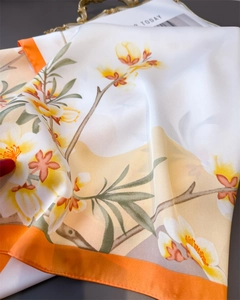 Détail macro d'un foulard en soie à fleurs avec une texture satinée orange et blanc
