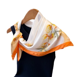 Foulard en imitation soie à fleurs jaunes et bordure orange sur un cintre bois